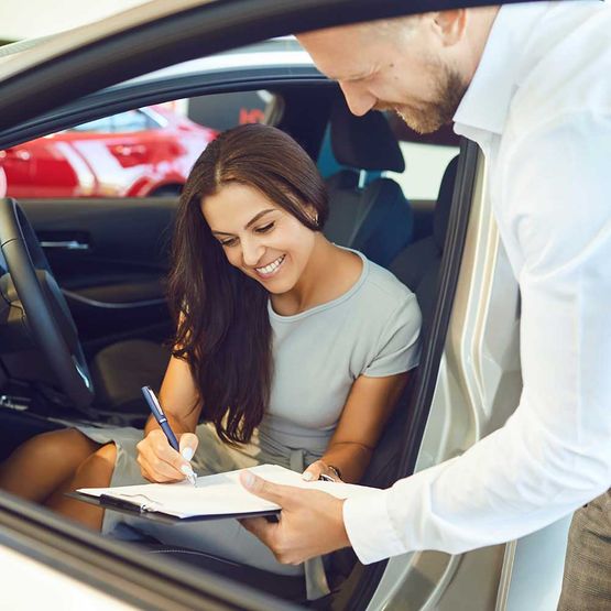 Eine junge Frau kauft ein Auto in einem Autohaus